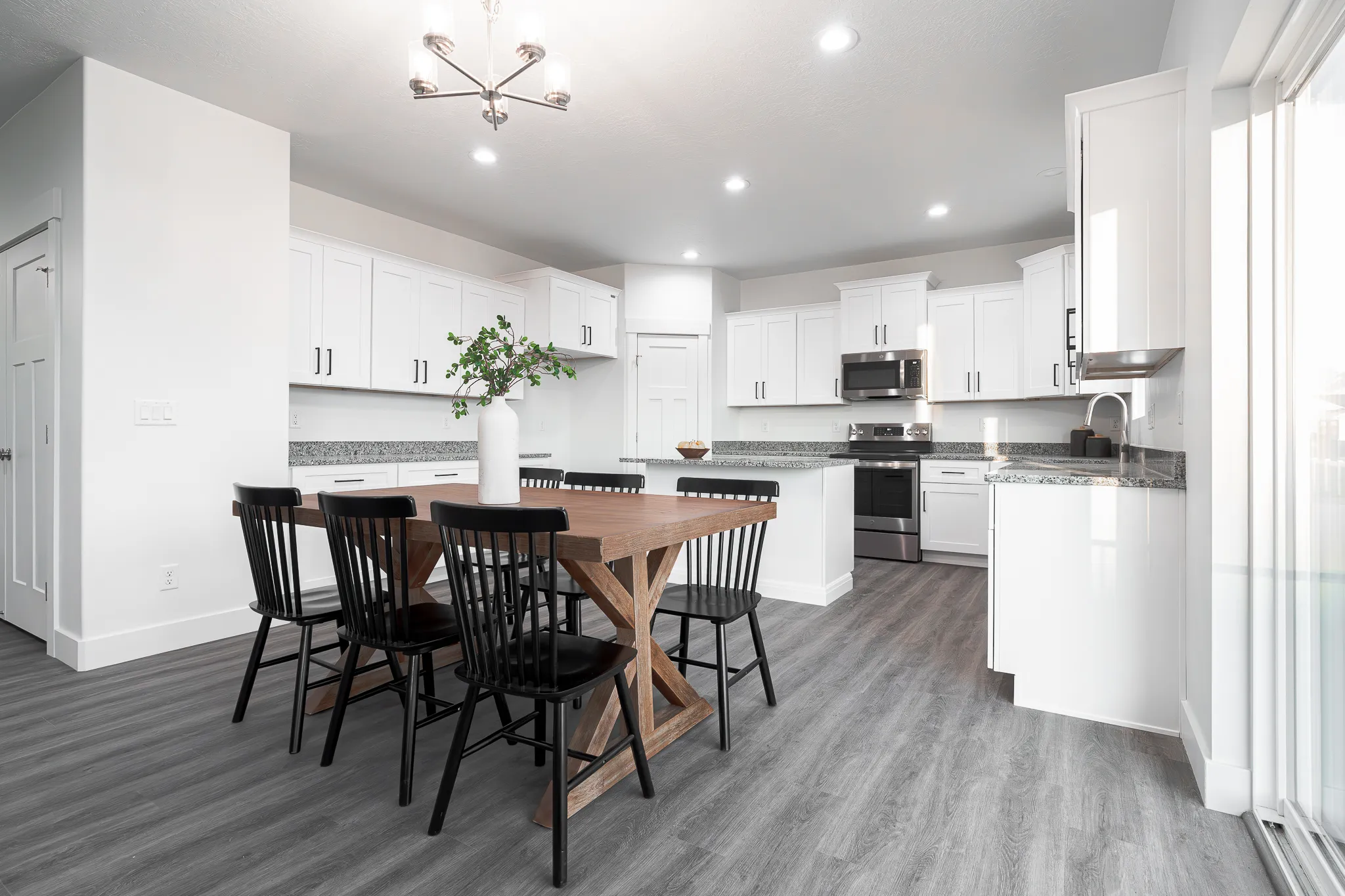 Bright staged kitchen and dining area with white cabinets